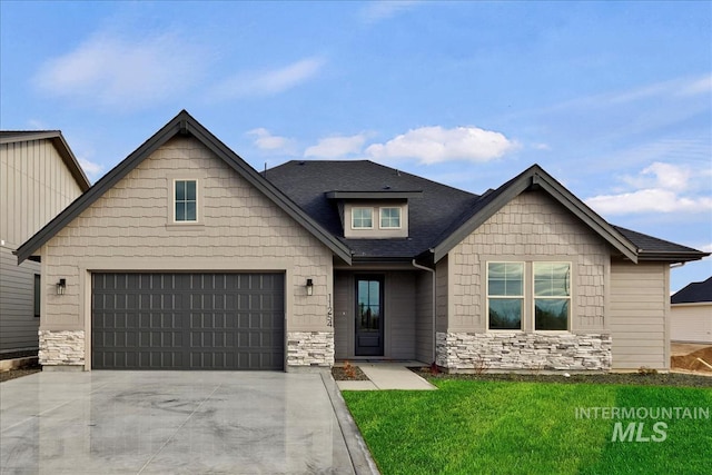 view of front of property with a garage, stone siding, driveway, roof with shingles, and a front yard