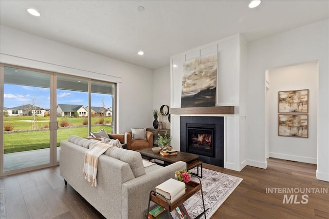 living area featuring a tile fireplace, baseboards, recessed lighting, and wood finished floors