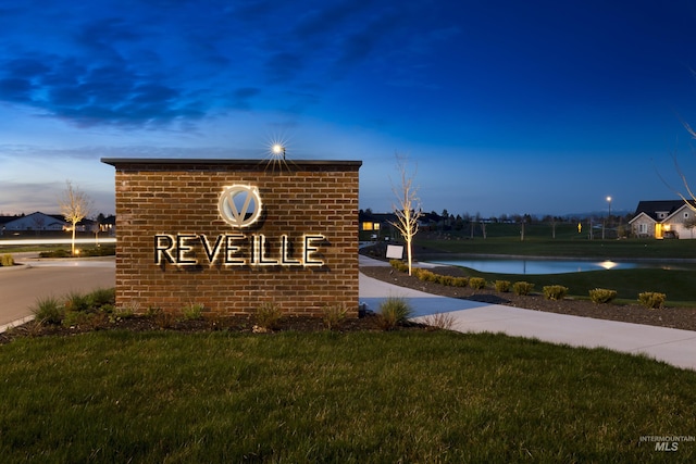 community sign featuring a water view and a yard