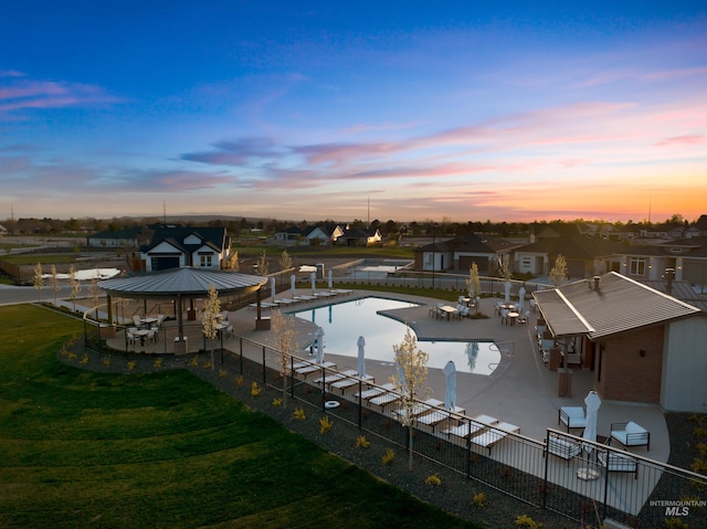 pool at dusk with a gazebo and a patio area