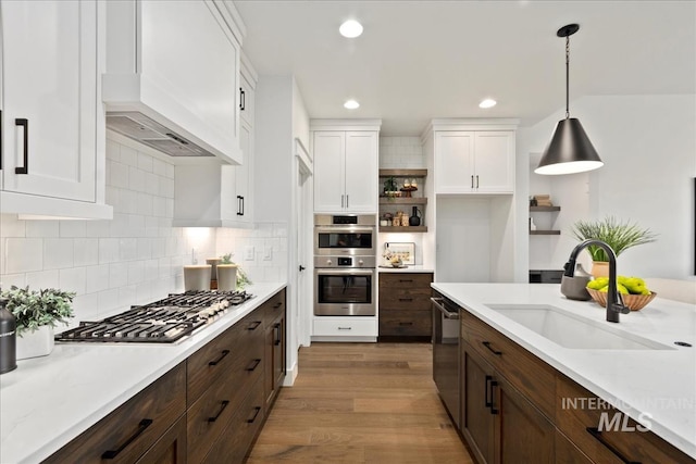 kitchen featuring open shelves, stainless steel appliances, light countertops, white cabinets, and a sink