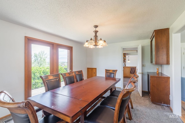 dining room with a textured ceiling, carpet floors, and a notable chandelier