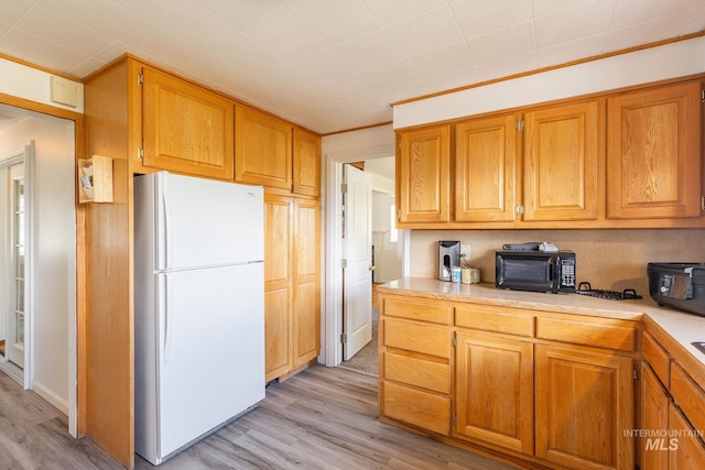 kitchen with white fridge, light wood-type flooring, and crown molding