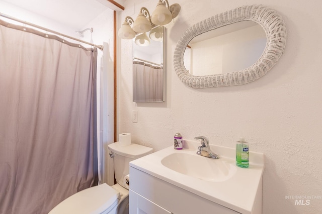 bathroom with curtained shower, vanity, and toilet