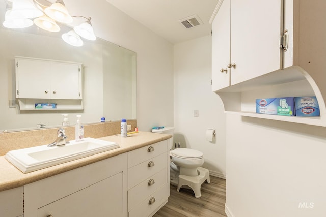 bathroom featuring vanity, hardwood / wood-style flooring, and toilet