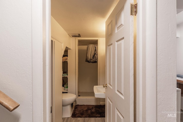 bathroom with a shower, wood-type flooring, and toilet