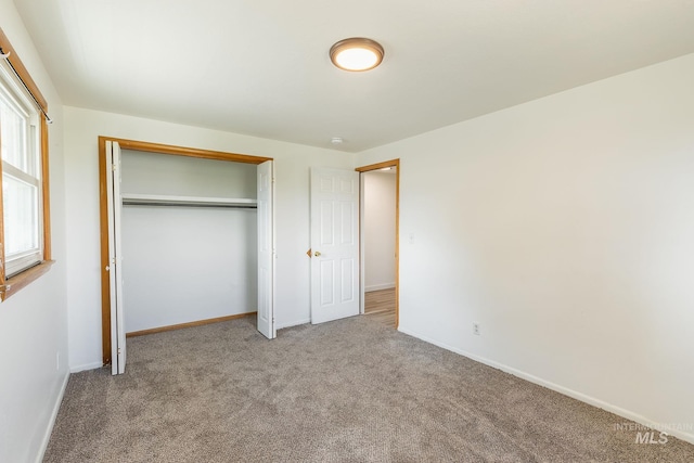 unfurnished bedroom featuring light carpet and a closet