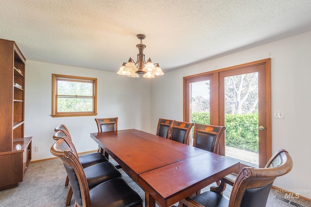 carpeted dining space featuring a healthy amount of sunlight, a chandelier, and a textured ceiling