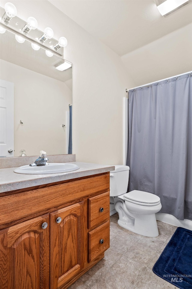 bathroom with toilet, vanity, and vaulted ceiling