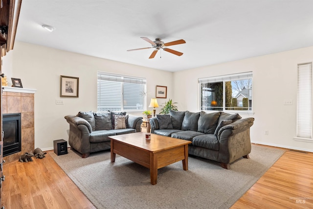 living room with a tile fireplace, ceiling fan, and hardwood / wood-style floors