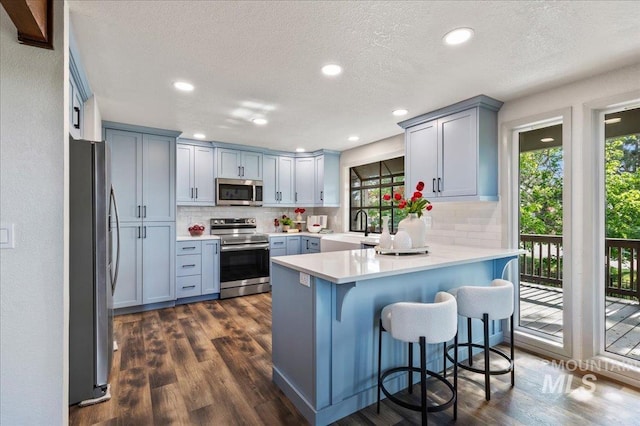 1909 E Roanoke Dr, Boise, ID 83712 - kitchen featuring appliances with stainless steel finishes, a peninsula, decorative backsplash, a sink, and a textured ceiling