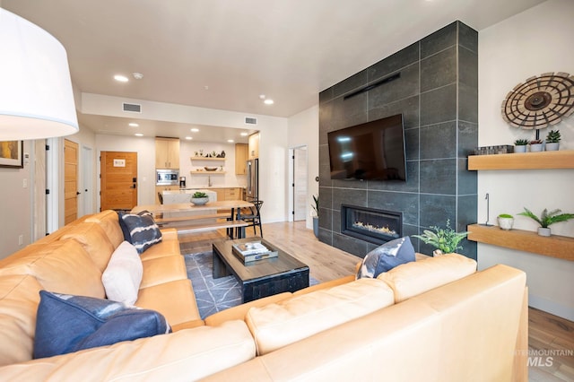 living room featuring a fireplace, tile walls, and wood-type flooring