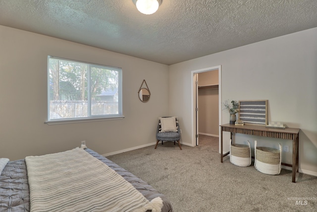 bedroom featuring a spacious closet, carpet flooring, a textured ceiling, and baseboards