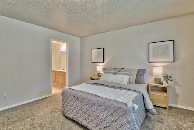 carpeted bedroom with baseboards, ensuite bathroom, and a textured ceiling