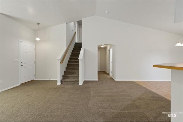 unfurnished living room featuring high vaulted ceiling, arched walkways, carpet flooring, baseboards, and stairs