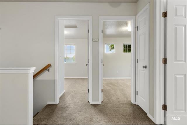 corridor featuring an upstairs landing, baseboards, and carpet floors