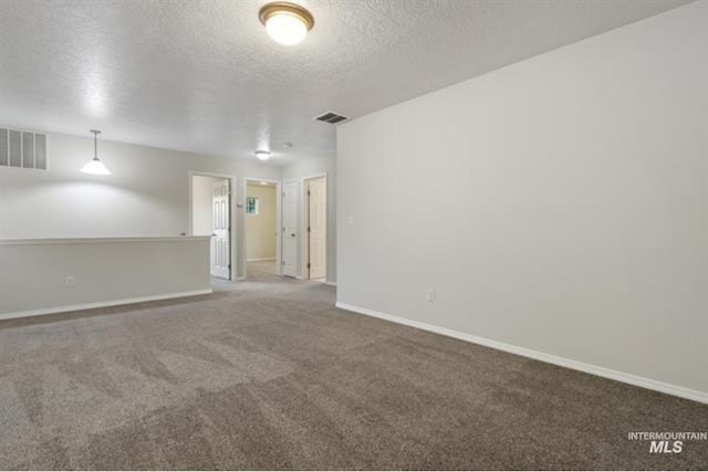 carpeted empty room featuring baseboards, visible vents, and a textured ceiling