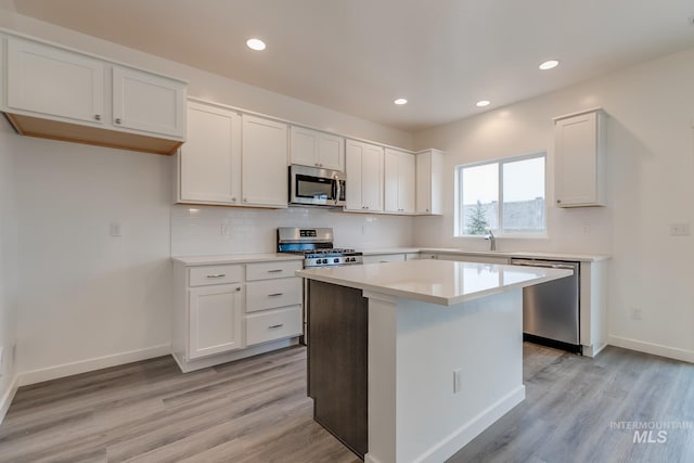 kitchen with appliances with stainless steel finishes, backsplash, white cabinetry, and light wood-style floors