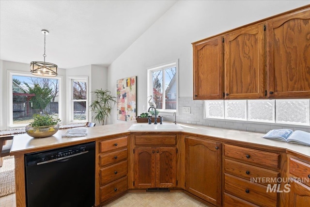 kitchen with dishwasher, a peninsula, vaulted ceiling, light countertops, and a sink