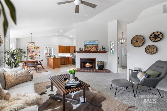 living area with light carpet, visible vents, vaulted ceiling, a brick fireplace, and ceiling fan with notable chandelier