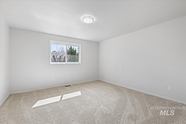 carpeted spare room featuring visible vents and baseboards