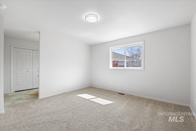 empty room featuring carpet floors, visible vents, and baseboards