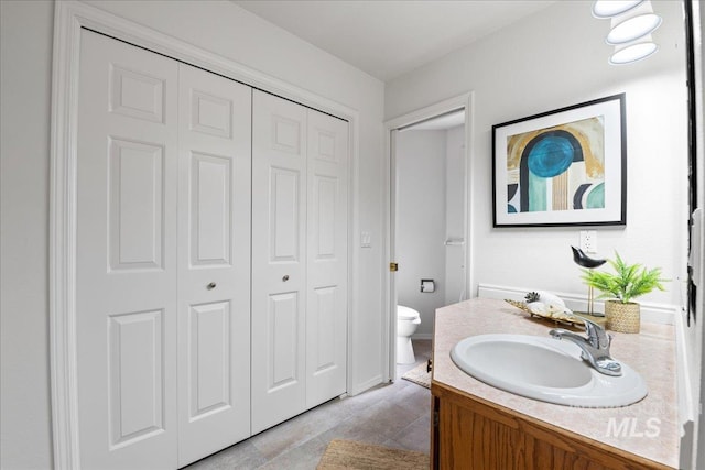 bathroom featuring toilet, a closet, and vanity