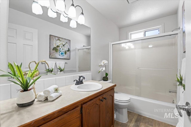 bathroom featuring toilet, bath / shower combo with glass door, wood finished floors, and vanity