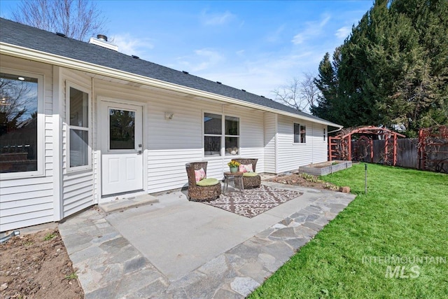 rear view of property with roof with shingles, a lawn, a patio, and fence