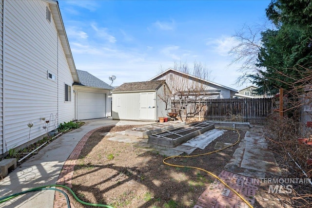 view of yard with an outbuilding, a vegetable garden, concrete driveway, a storage shed, and fence