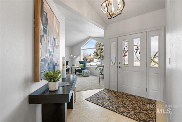 foyer entrance featuring lofted ceiling, carpet floors, a notable chandelier, and a textured wall