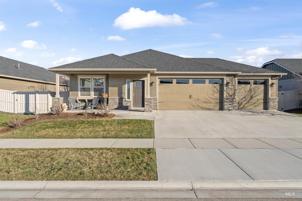 prairie-style house featuring a porch, a front yard, and a garage