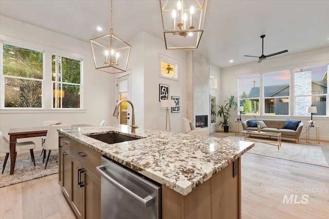 kitchen featuring a sink, stainless steel dishwasher, a chandelier, light wood-style floors, and healthy amount of natural light