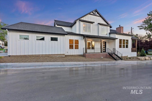 modern farmhouse style home with board and batten siding, a porch, and a chimney