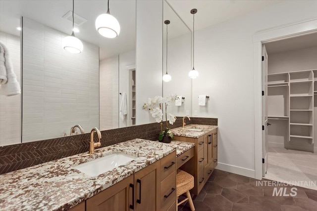 bathroom featuring vanity, a spacious closet, baseboards, and tile patterned floors