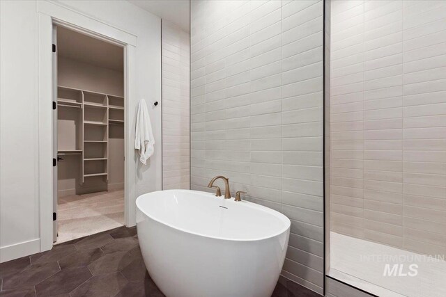 full bathroom featuring a spacious closet, a soaking tub, and a walk in shower