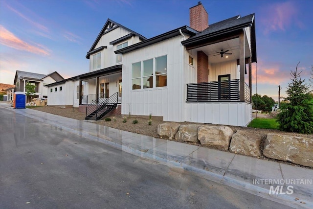 modern farmhouse style home featuring a chimney, ceiling fan, board and batten siding, and stairway