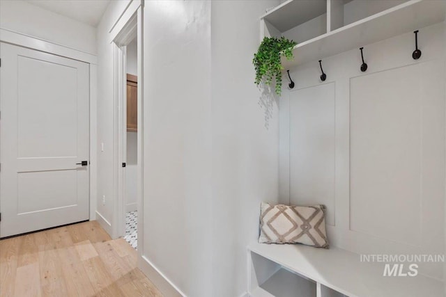 mudroom featuring light wood finished floors and baseboards