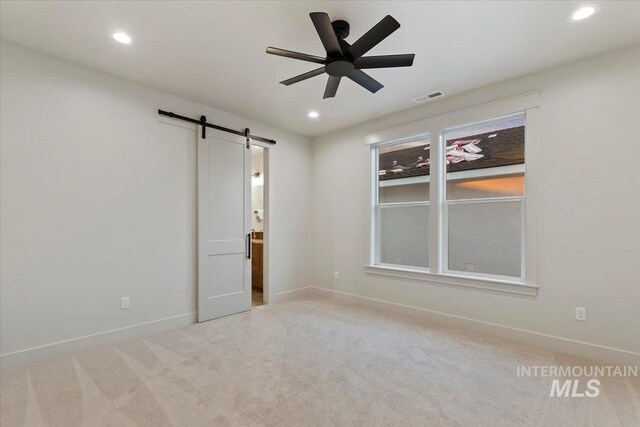 carpeted empty room with a barn door, recessed lighting, baseboards, and a ceiling fan
