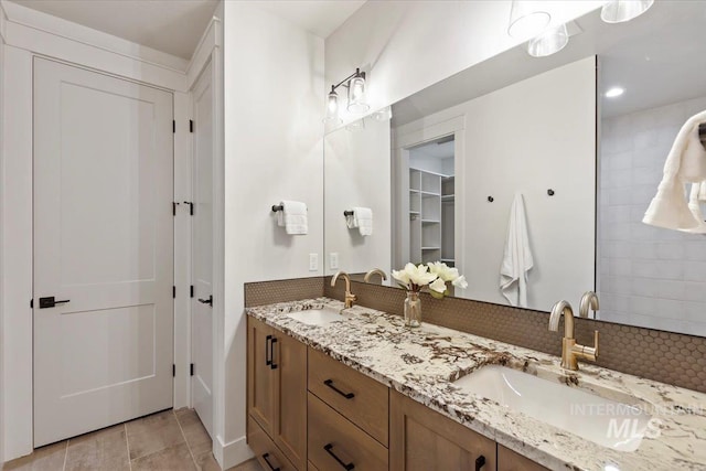 full bathroom featuring double vanity, backsplash, and a walk in closet
