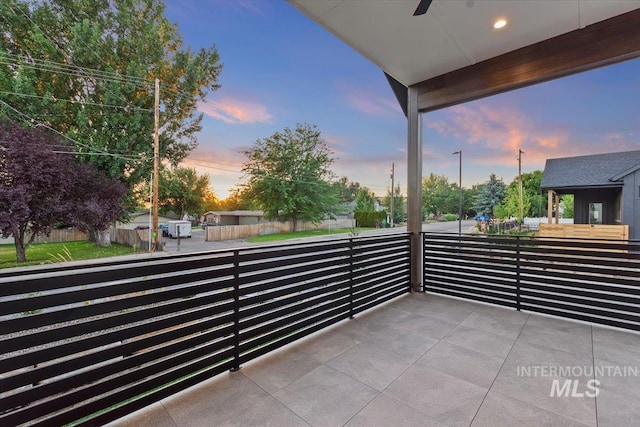 balcony at dusk featuring ceiling fan
