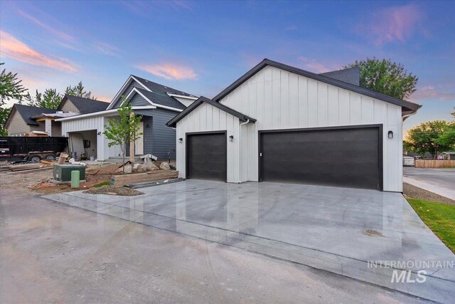 modern inspired farmhouse with an attached garage, board and batten siding, and concrete driveway