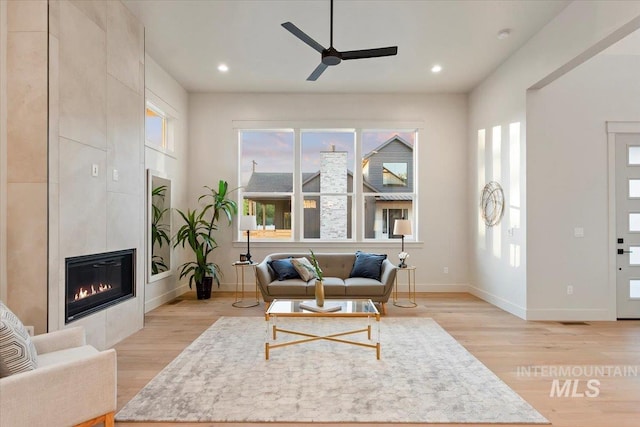 living area featuring ceiling fan, light wood-style floors, baseboards, recessed lighting, and a fireplace