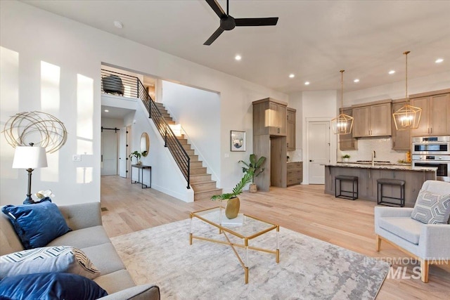 living room with light wood finished floors, ceiling fan, recessed lighting, stairs, and baseboards