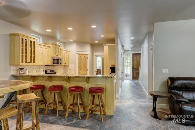 12507 N Humphreys Way, Boise, ID 83714 - kitchen with stainless steel appliances, stone tile floors, glass insert cabinets, baseboards, and light brown cabinetry
