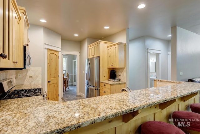 12507 N Humphreys Way, Boise, ID 83714 - kitchen featuring appliances with stainless steel finishes, light brown cabinetry, recessed lighting, tasteful backsplash, and light stone counters