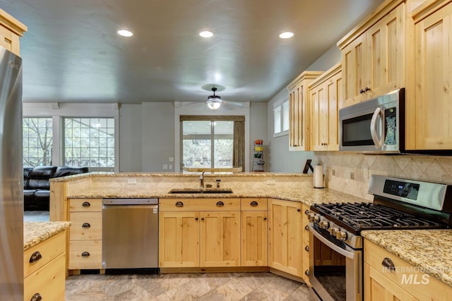 12507 N Humphreys Way, Boise, ID 83714 - kitchen featuring appliances with stainless steel finishes, a sink, light brown cabinetry, a peninsula, and backsplash