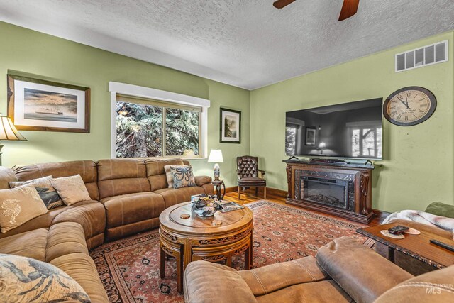 911 Davis, Mccall, ID 83638 - living room with a ceiling fan, a textured ceiling, wood finished floors, a glass covered fireplace, and baseboards