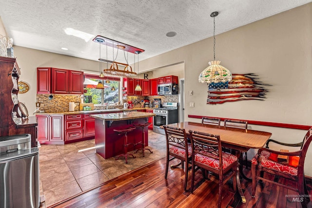 911 Davis, Mccall, ID 83638 - kitchen with appliances with stainless steel finishes, reddish brown cabinets, backsplash, a kitchen island, and a textured ceiling