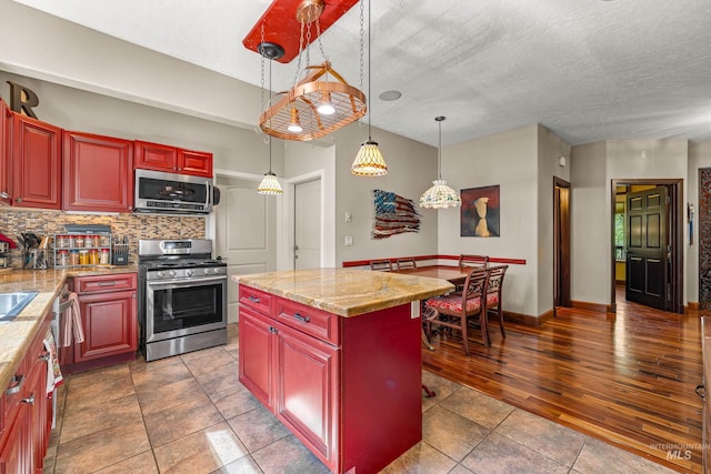 911 Davis, Mccall, ID 83638 - kitchen with appliances with stainless steel finishes, tasteful backsplash, reddish brown cabinets, hanging light fixtures, and dark tile patterned floors